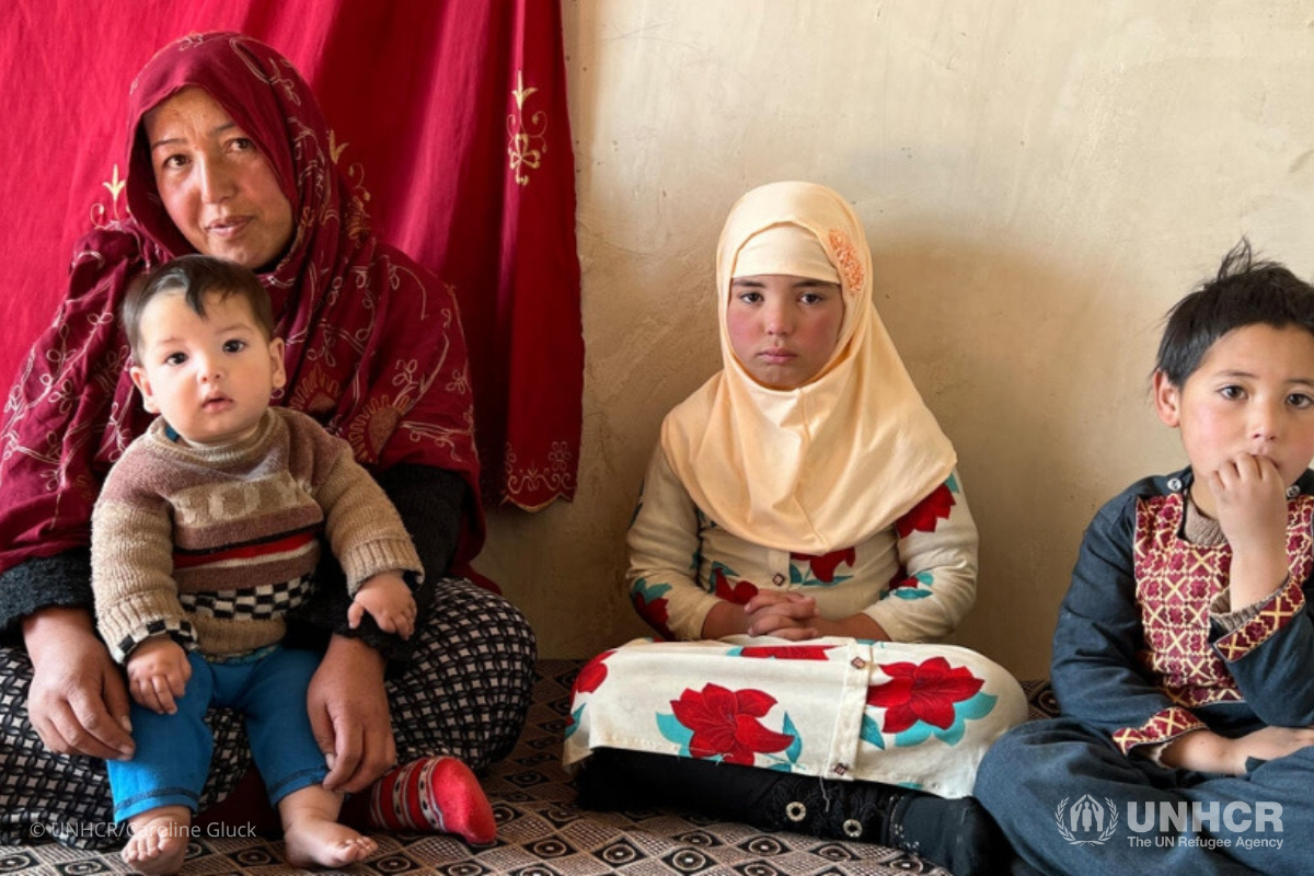 Sara sits on the floor with her children. Sara was two months pregnant when her husband died a year and a half ago.