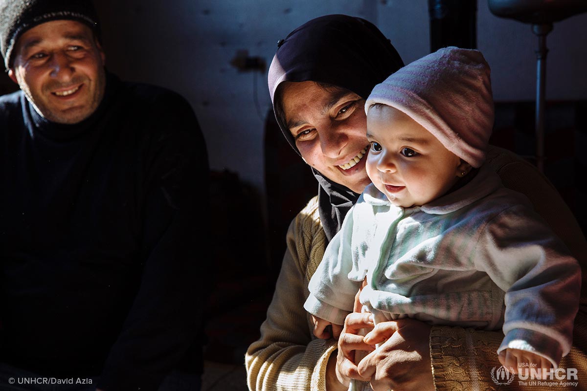 Syrian refugee Samira, 38, holds her six-month-old niece Mona alongside her husband Khaled, 45, a Palestinian refugee displaced from Syria, on the floor of the apartment they share with their family