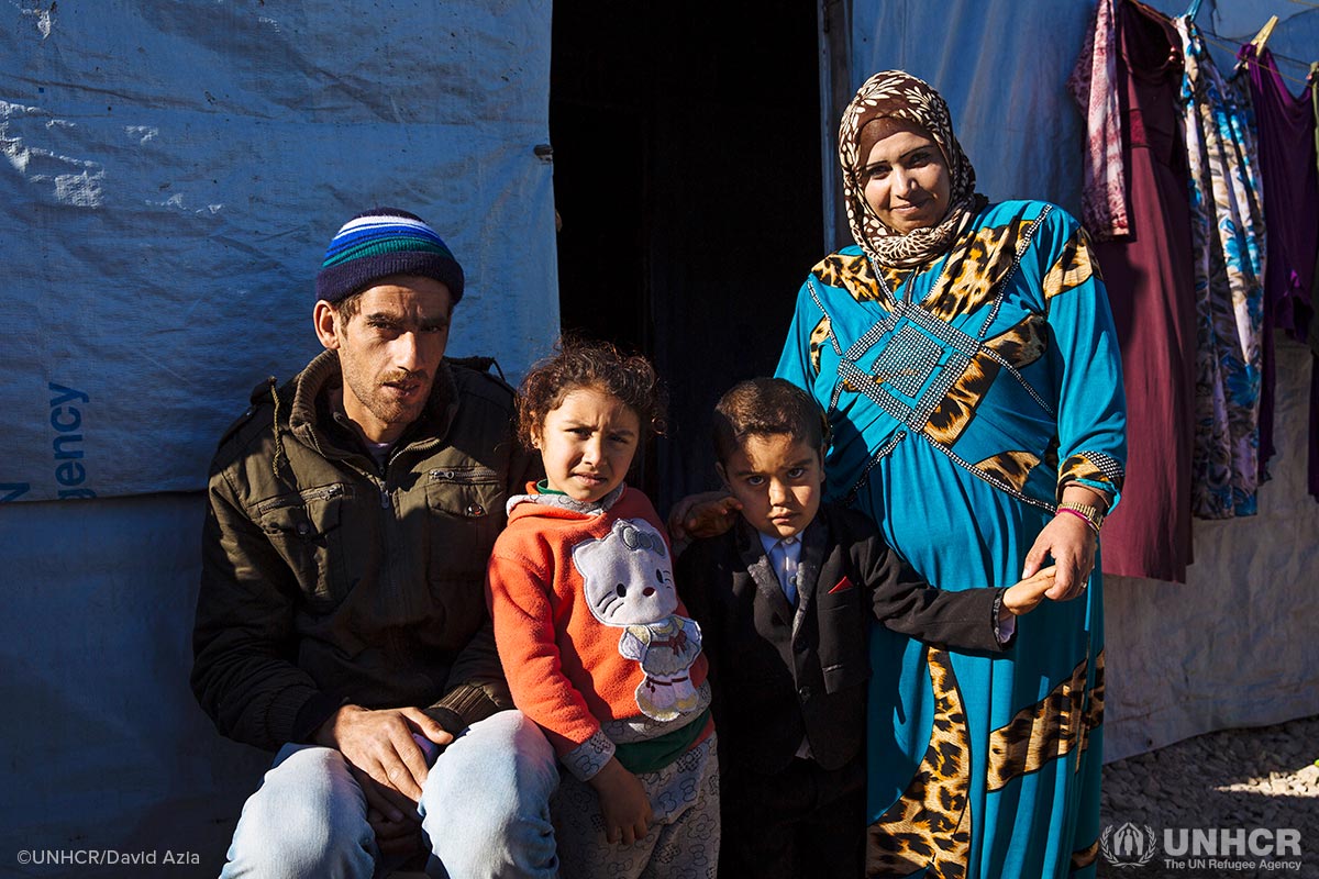 Syrian refugees Hamra, Malek and their young children, Shahad and Ahmed, stand in front of their shelter for the winter in Lebanon.