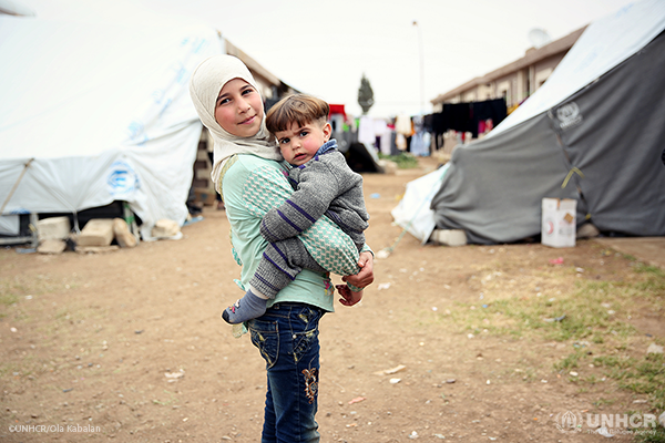 A young girl carries her brother through the Herjalleh shelter in rural Damascuc where they are staying after fleeing fighting in Eastern Ghouta.