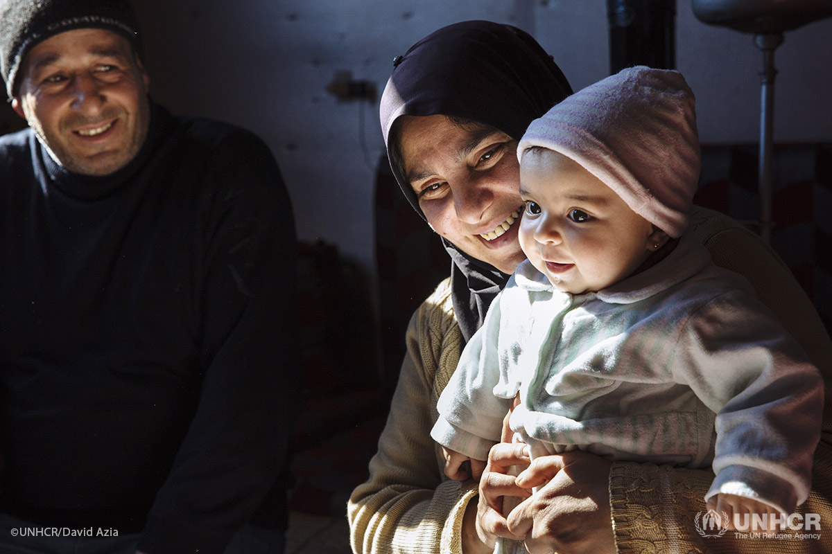 Syrian refugee Samira, 38, holds her six-month-old niece Mona alongside her husband Khaled, 45, a Palestinian refugee displaced from Syria, on the floor of the apartment they share with their family in a substandard building in Barelias, Bekaa Valley, Lebanon.