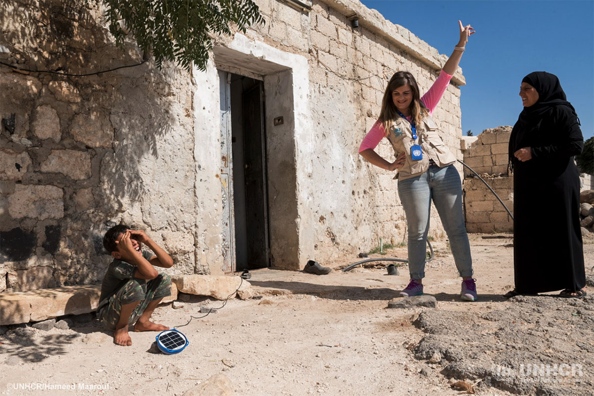 Moayyed, his mother and a UNHCR protection officer install the family's new solar light.