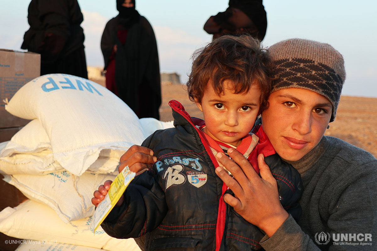 A young child drinks a nutritional supplement at the aid distribution point.