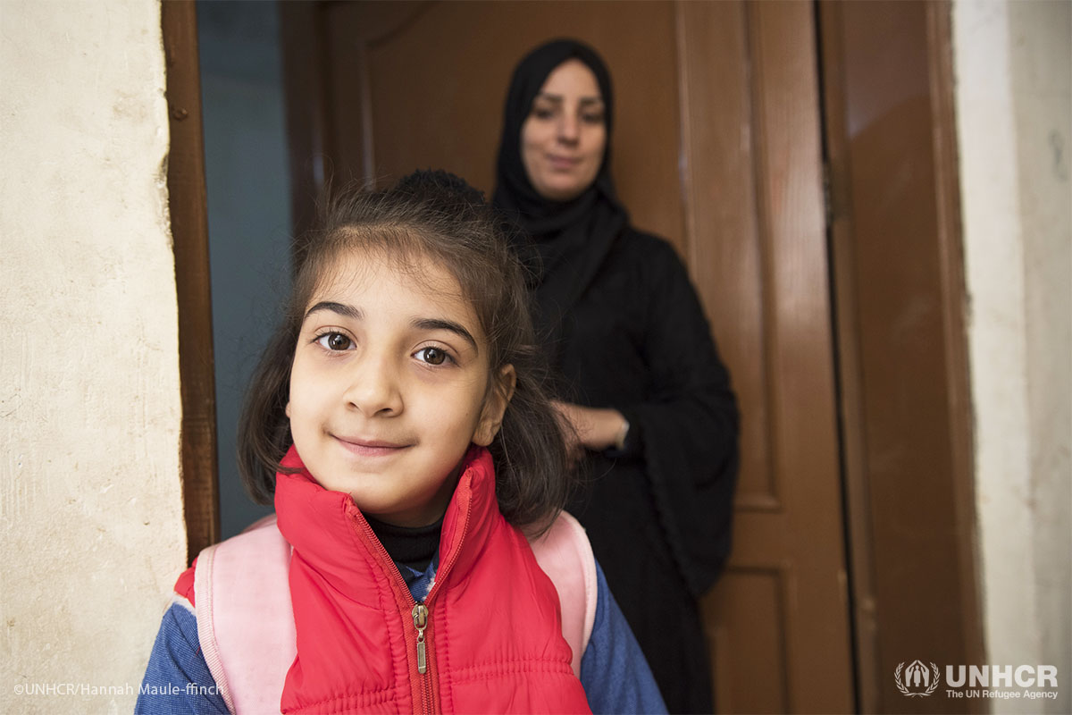 Entesar helps her daughter Kholud to get ready for school, outside of their home.