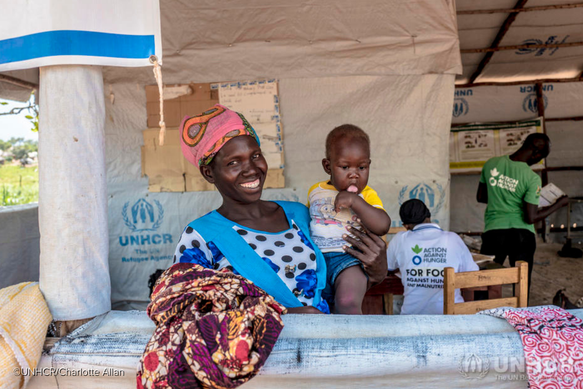 Smiling South Sudanese mother holds her baby