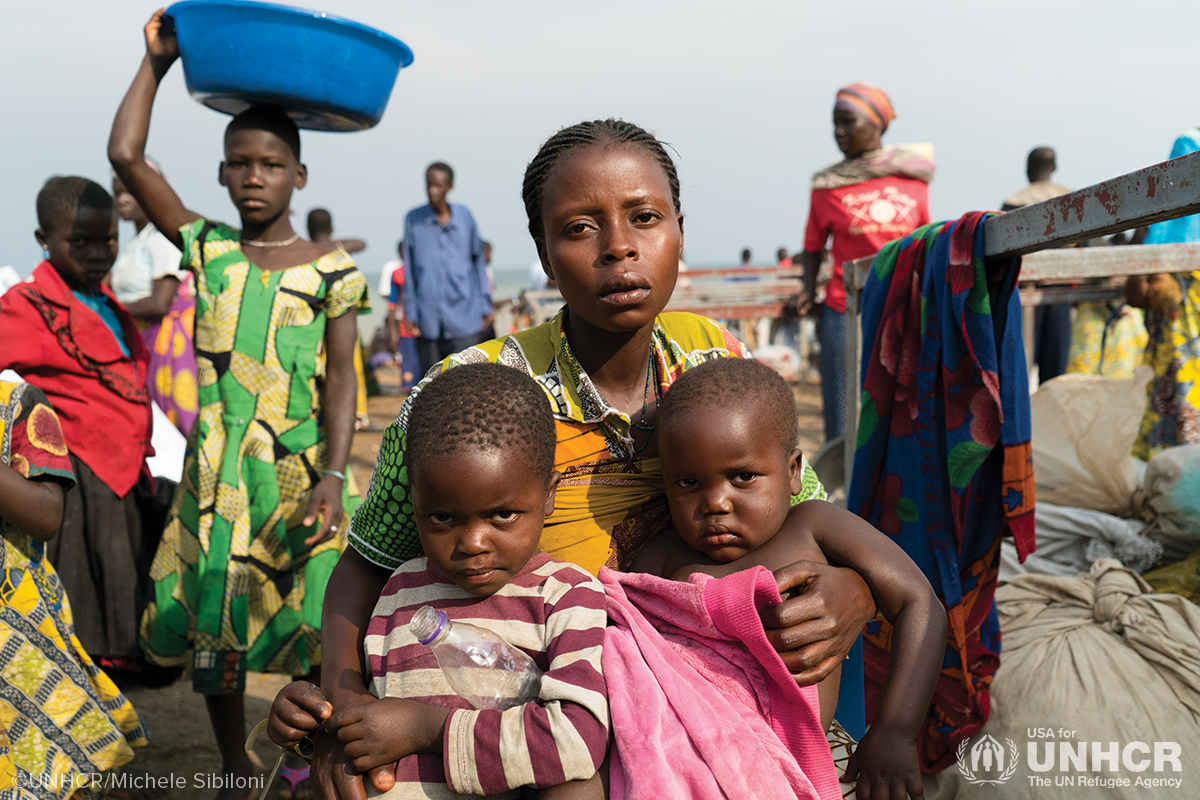 woman sits with her two children in crowd