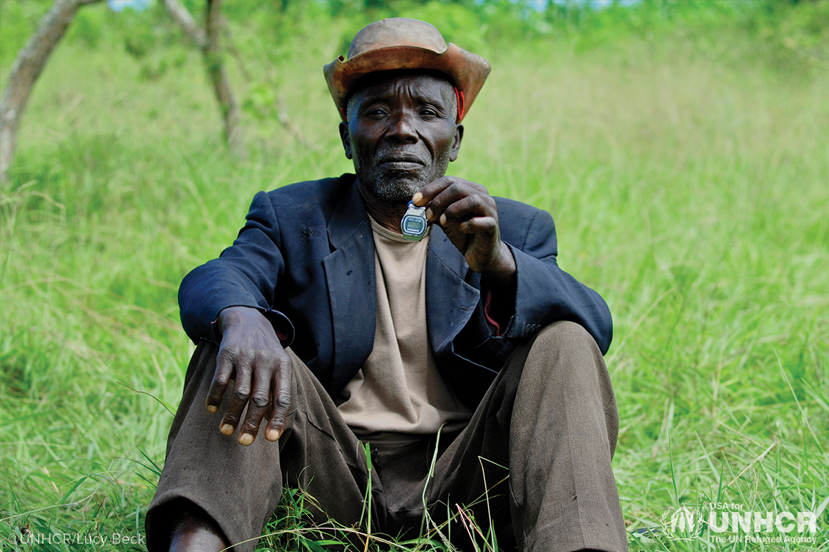 gabriel sitting in the grass holding up a watch