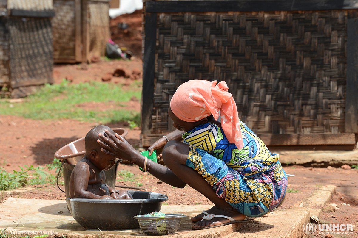 woman washes her child in basin with clean water