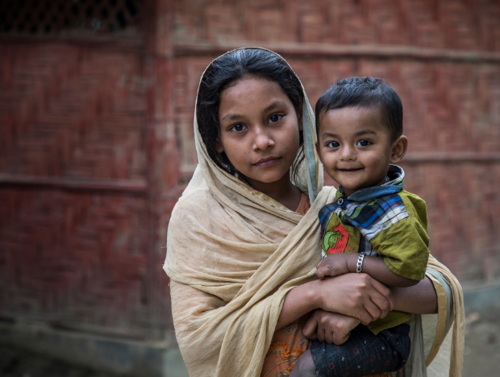 Portrait of a young Rohingya girl holding her brother