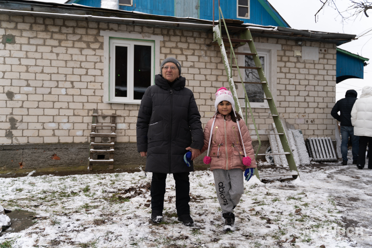 Tamara and her granddaughter stand outside their home which was damaged