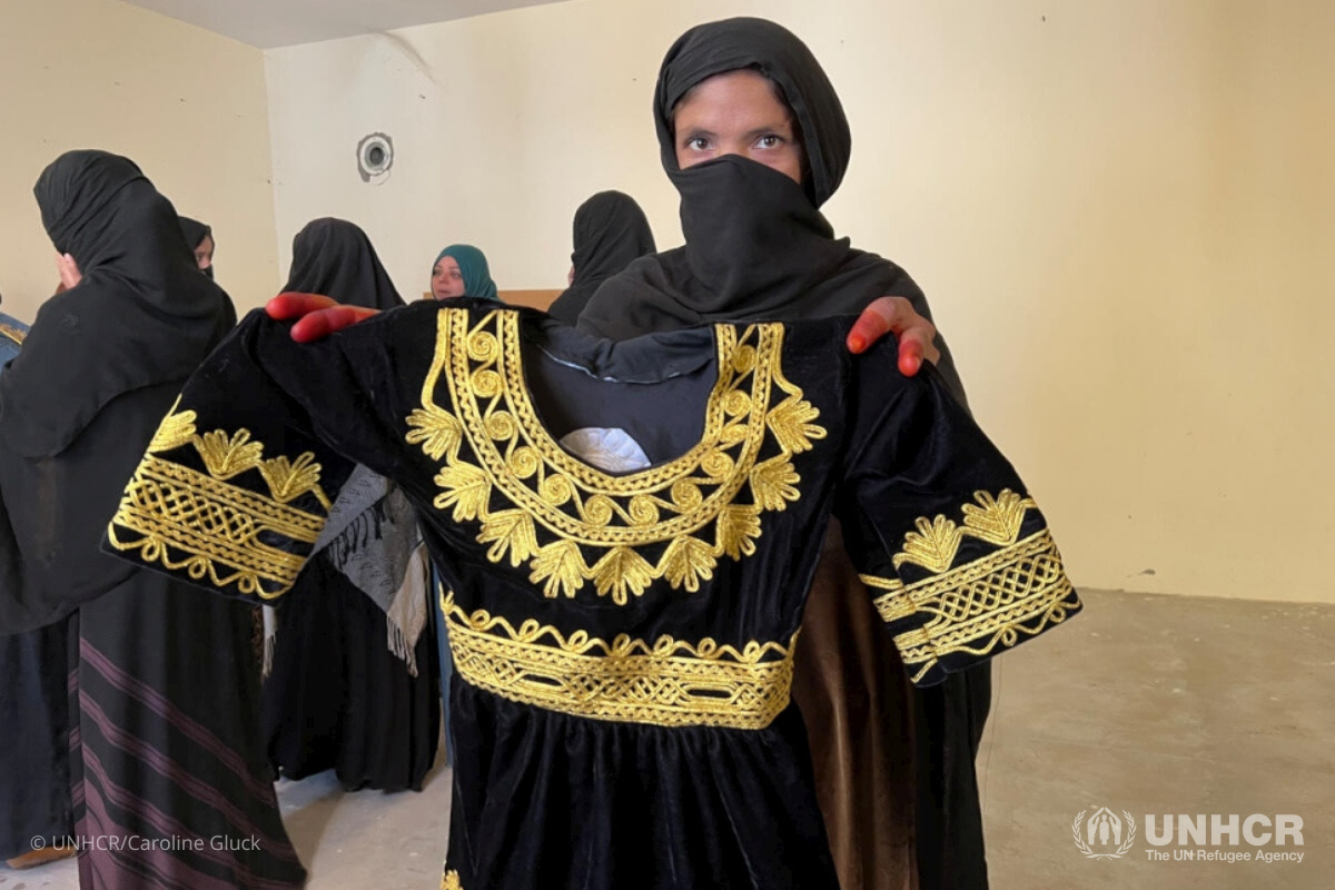 One of the women who received training through the programme holds up a garment she made. 