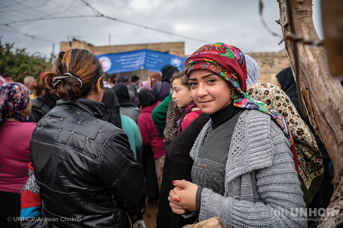 young syrian refugee woman waits for aid supplies