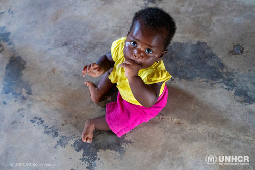 A baby from Burundi sits on the floor while being registered in the Democratic Republic of Congo.