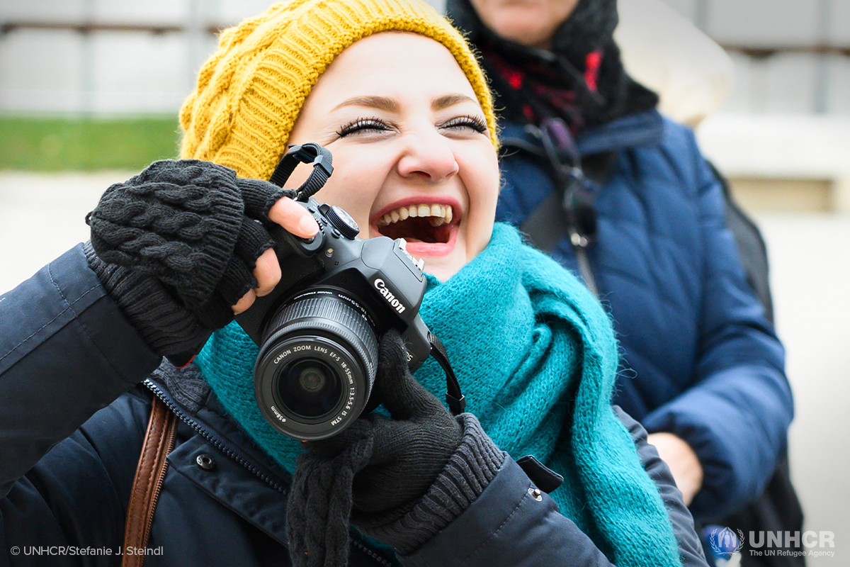 syrian refugee woman laughing while taking photos with her camera