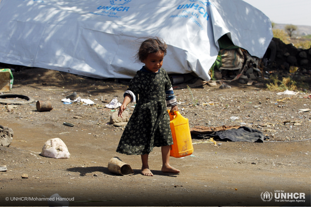 Yemeni girl, Halimah Khaled, carries a jerry can used for collecting water as she walks outside her family's tent at the Dharawan settlement, Yemen.