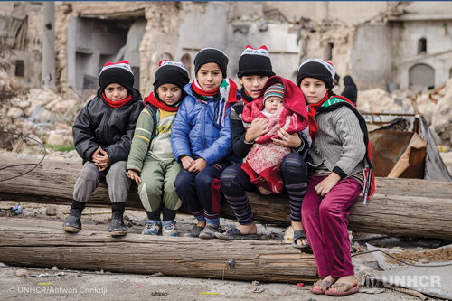 syrian refugee children sit outside a unhcr community center