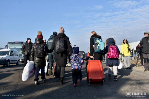 Families carry their belongings through the Zosin border crossing in Poland after fleeing Ukraine.