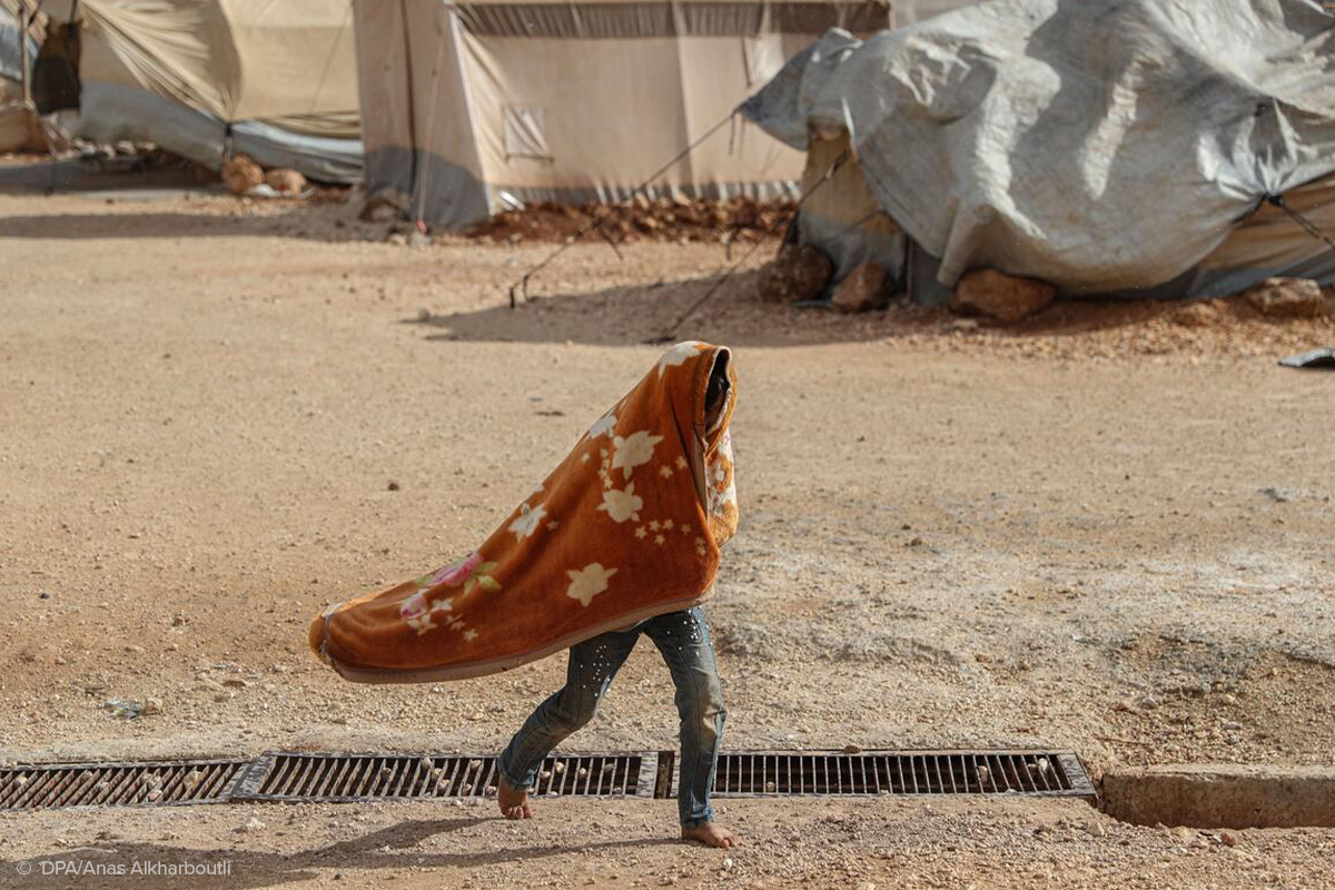 A child walks across Al-Rahma camp for displaced people in north-western Syria during a severe wind storm that hit the area in December