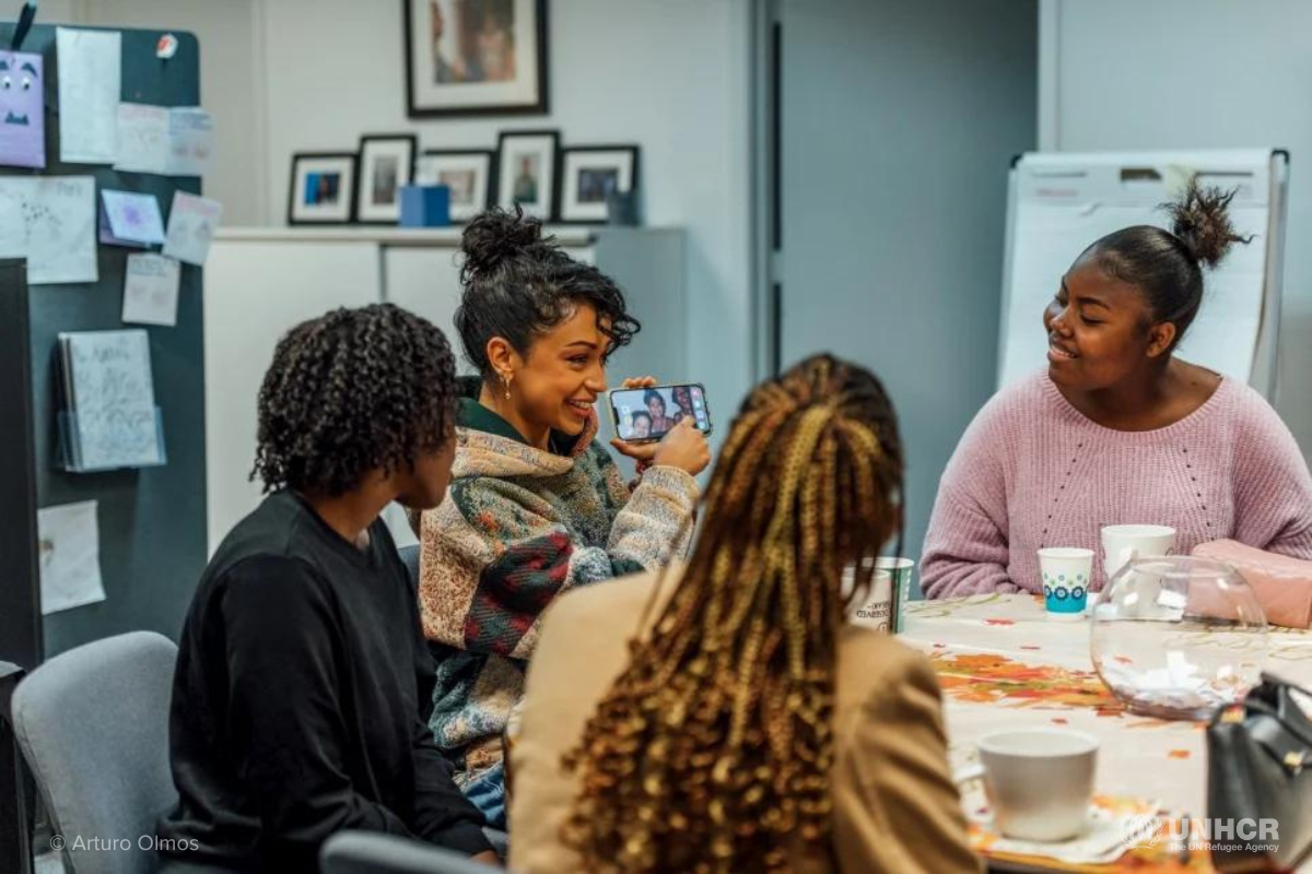 UNHCR high profile supporter Liza Koshy speaks with resettled refugee girls during a Thanksgiving meal.